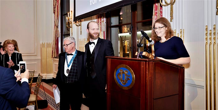  Madeline Miller (l.) introduces Michael Putnam (with medal).
